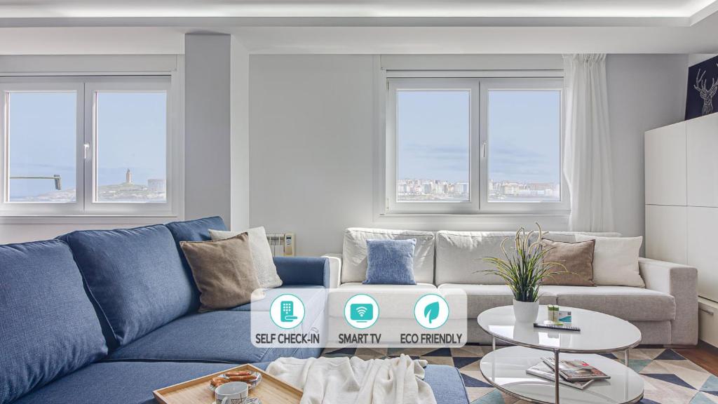 a living room with a blue couch and windows at Riazor Ocean View Apartment in A Coruña