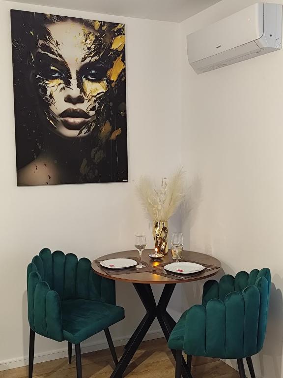 a dining room with a table and two green chairs at Vivien Residence 2 in Baia Mare