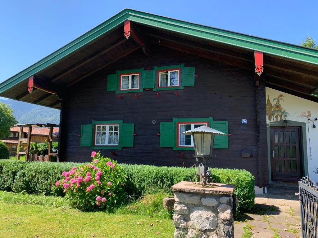 a black house with green windows and a porch at Haus Bergsteigerglück in Schleching