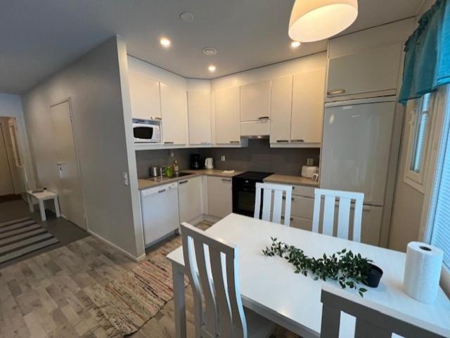 a kitchen with white cabinets and a table and chairs at Apartment Annalantie in Pyhäjoki