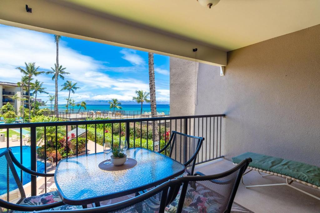 a balcony with a table and chairs and the ocean at Hale Ono Loa 204 in Lahaina