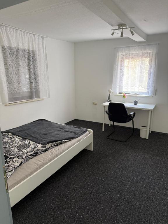 a bedroom with a bed and a desk and a chair at Zimmervermietung Kimberly in Bischbrunn