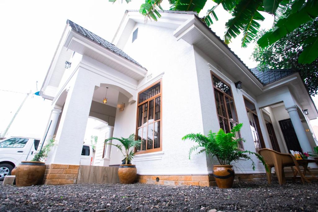 a white house with potted plants in front of it at Tunji Homestay in Arusha