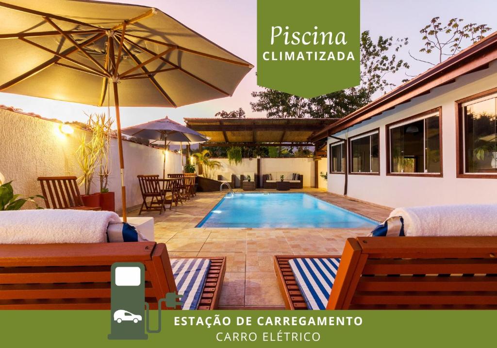 a villa with a swimming pool and an umbrella at Pousada Recanto do Jabaquara in Paraty
