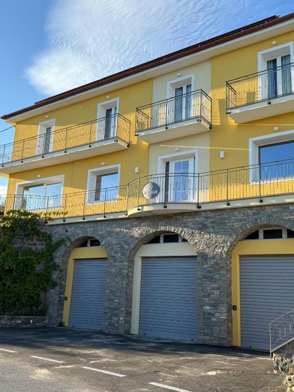 a yellow building with four garage doors on it at Agriturismo De Ferrari in Onzo