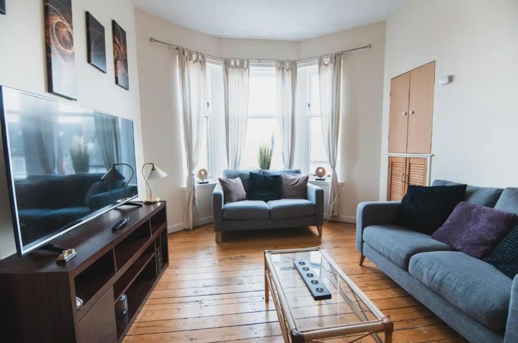 a living room with a couch and a tv at Causeyside apartment in Paisley