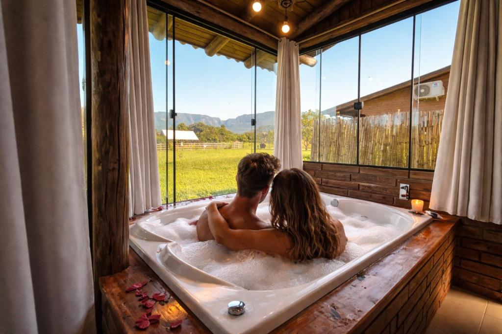 a man and woman sitting in a bath tub at Chalés Aconchego dos Canyons in Praia Grande