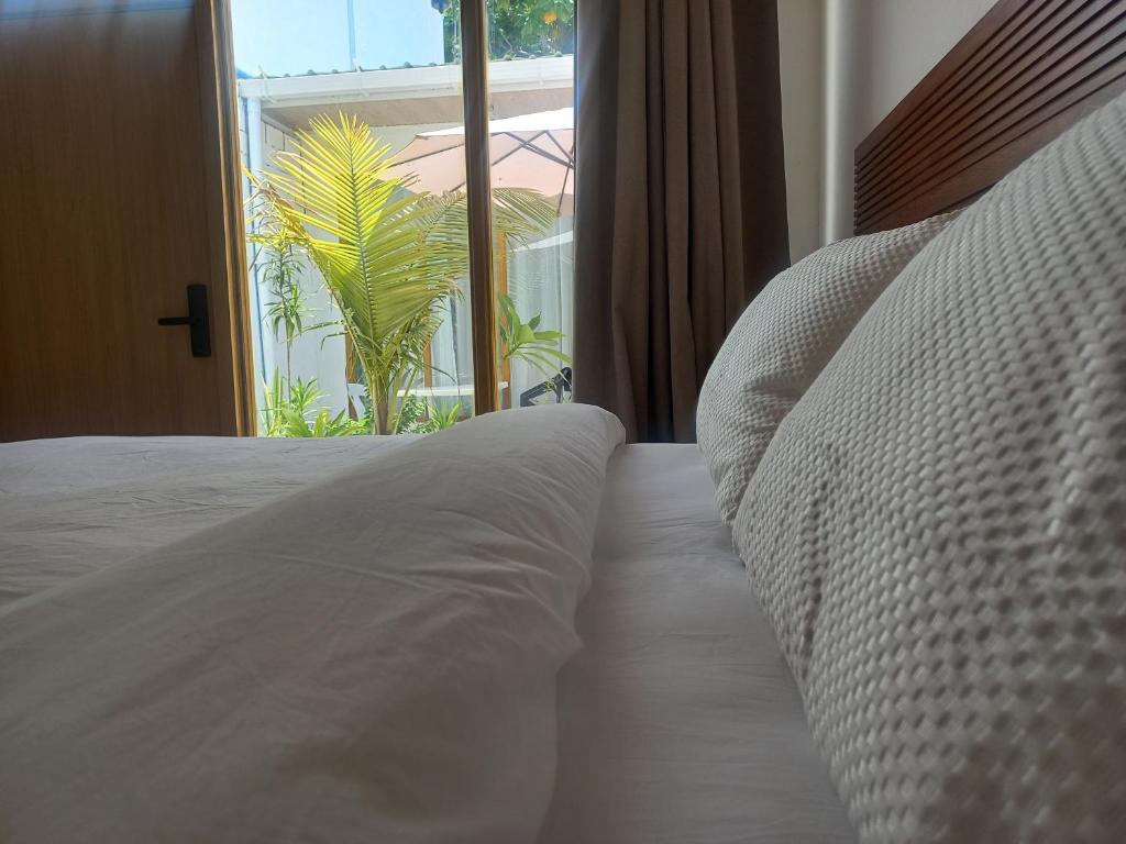 a white bed in a room with a window at Dhigurah Holidays in Dhigurah