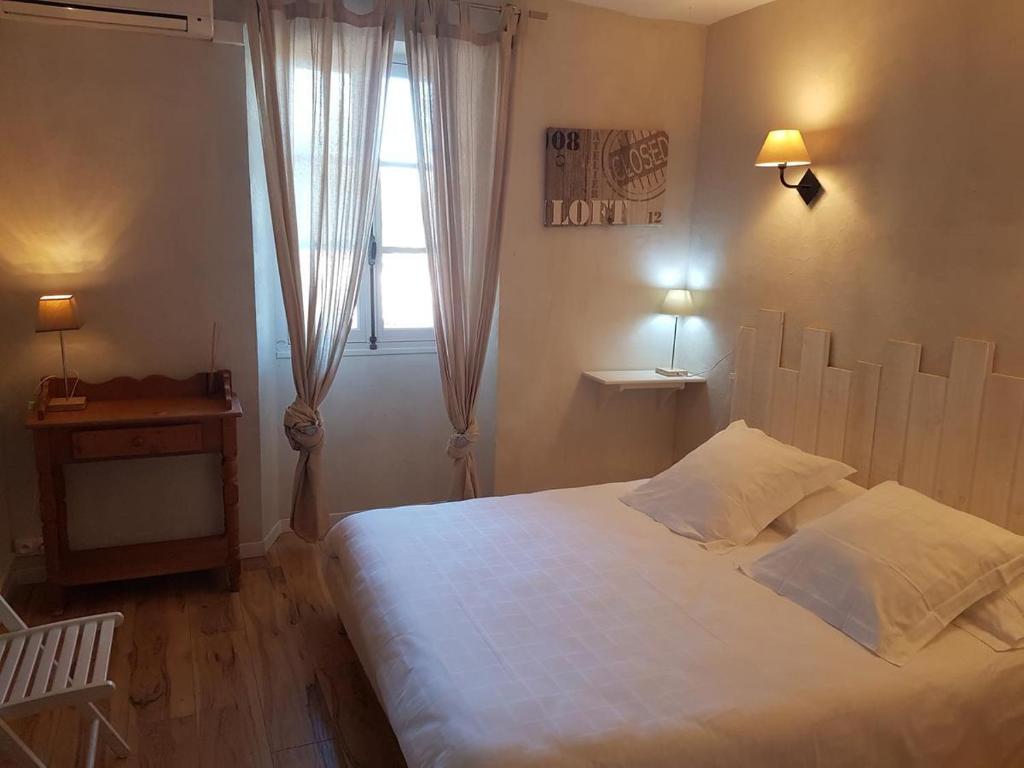 a bedroom with a white bed and a window at Hôtel Le Niobel in Belgodère