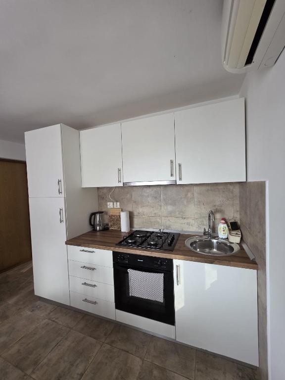 a kitchen with white cabinets and a stove and a sink at Studio apartman Vrba in Otočac