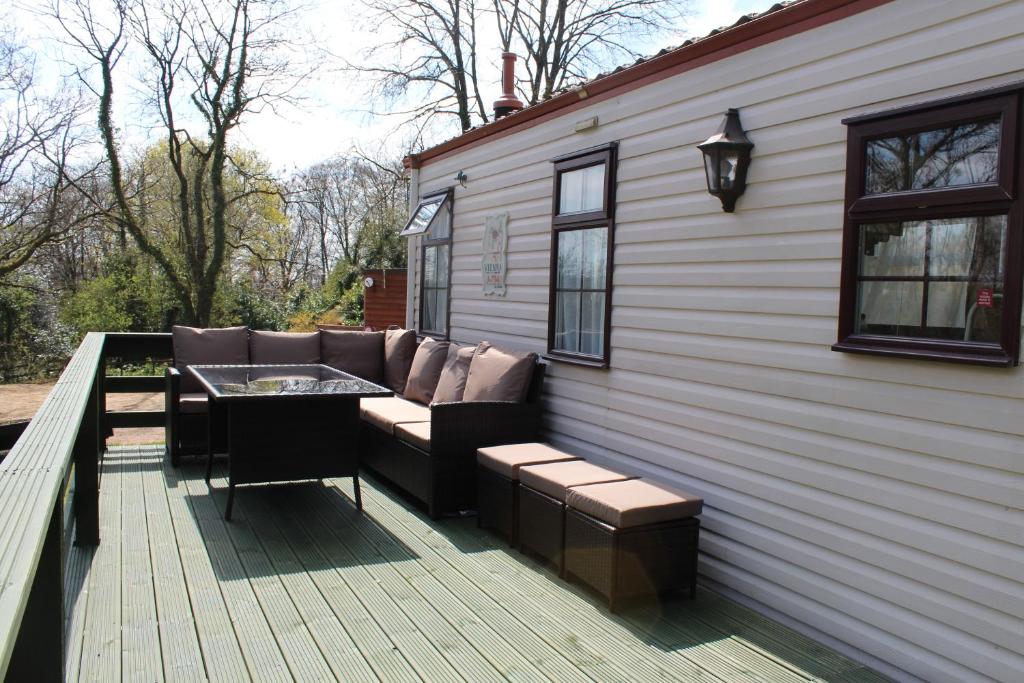 a patio with a couch and a table on a deck at The Willows at Kingsmead Camping in West Buckland