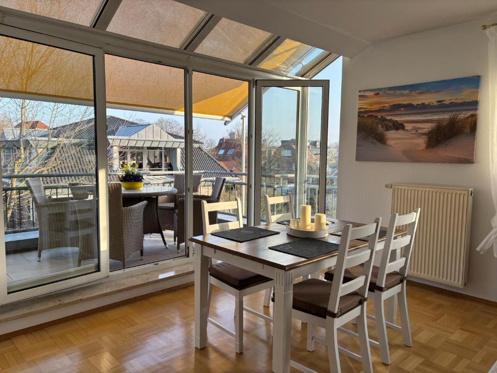 a dining room with a table and chairs and a balcony at MeerZeit in Bad Zwischenahn