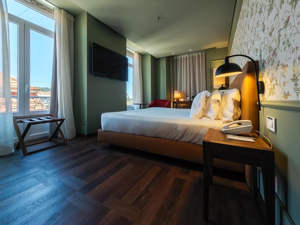 A bright guest room with a double bed, writing desk and tall windows.
