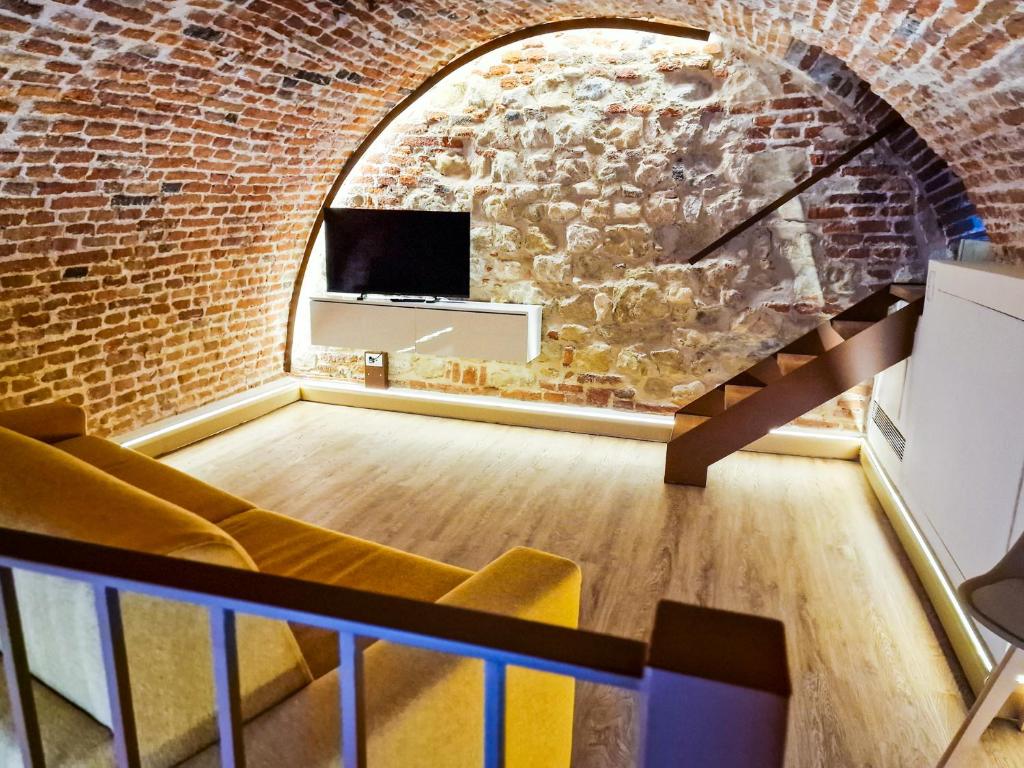 an attic room with a brick wall and a tv at Il Rivellino in Marostica