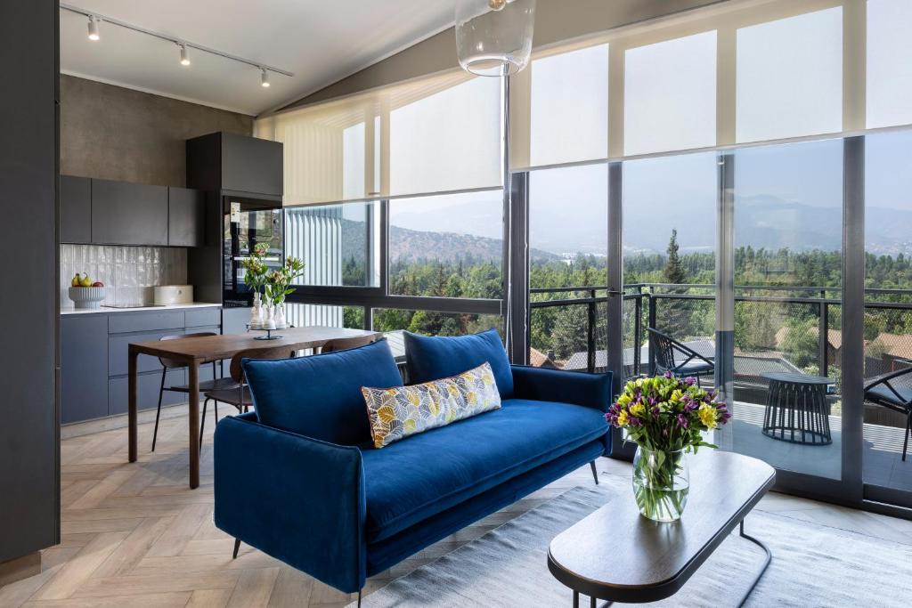 a living room with a blue couch and a kitchen with windows at Pueblo La Dehesa in Santiago