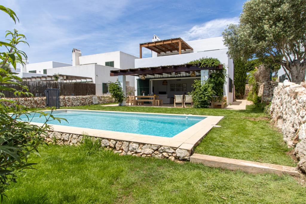 a villa with a swimming pool in front of a house at Villa Conguitosby 3VILLAS in Sant Lluis