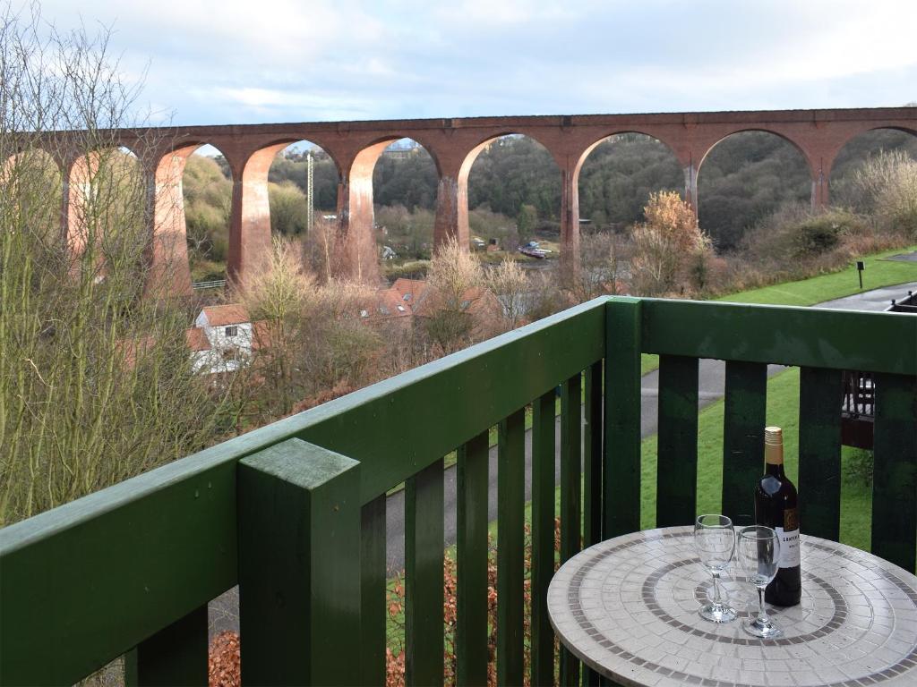 a table with wine glasses on a balcony with a bridge at Capstan Cottage in Whitby