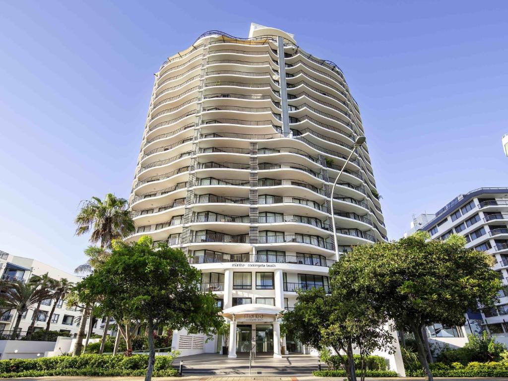 a tall white building with trees in front of it at Mantra Coolangatta Beach in Gold Coast