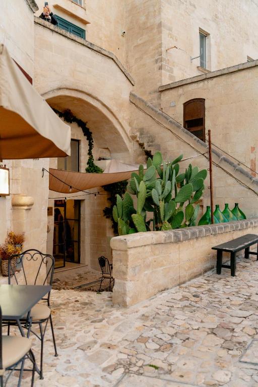 a patio with chairs and a table and a plant at Palazzo Del Duca Hotel & Restaurant in Matera