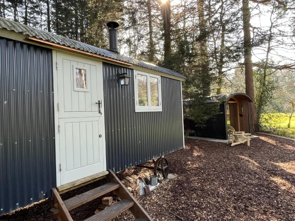 a black and white tiny house with a garage at Chez Marguerite Luxury Shepherd's Hut and Sauna in Holt