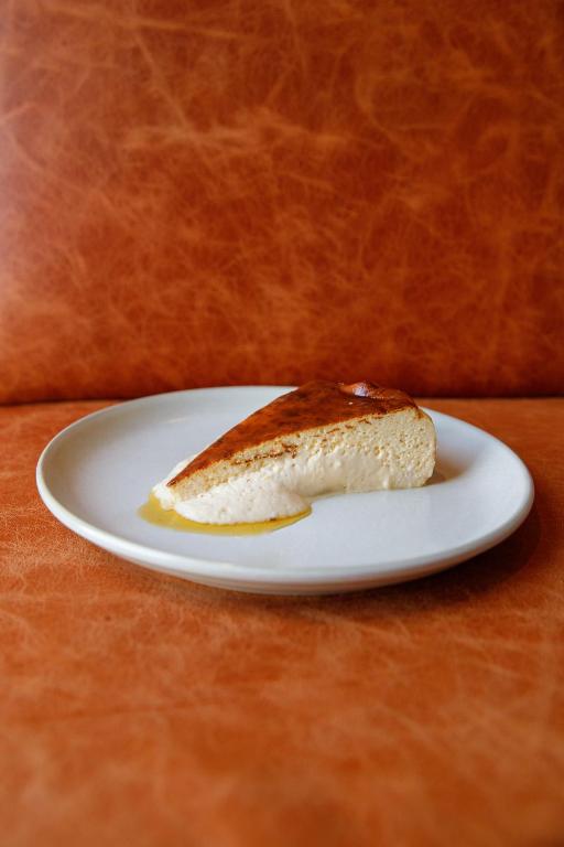 A plated slice of cake or pastry served against orange leather seating.