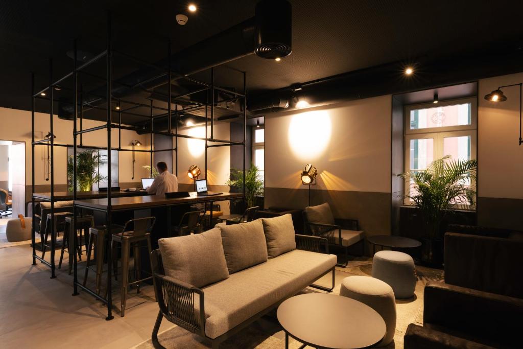 A warmly lit hotel lounge with sofas, round tables, and a built-in bar.