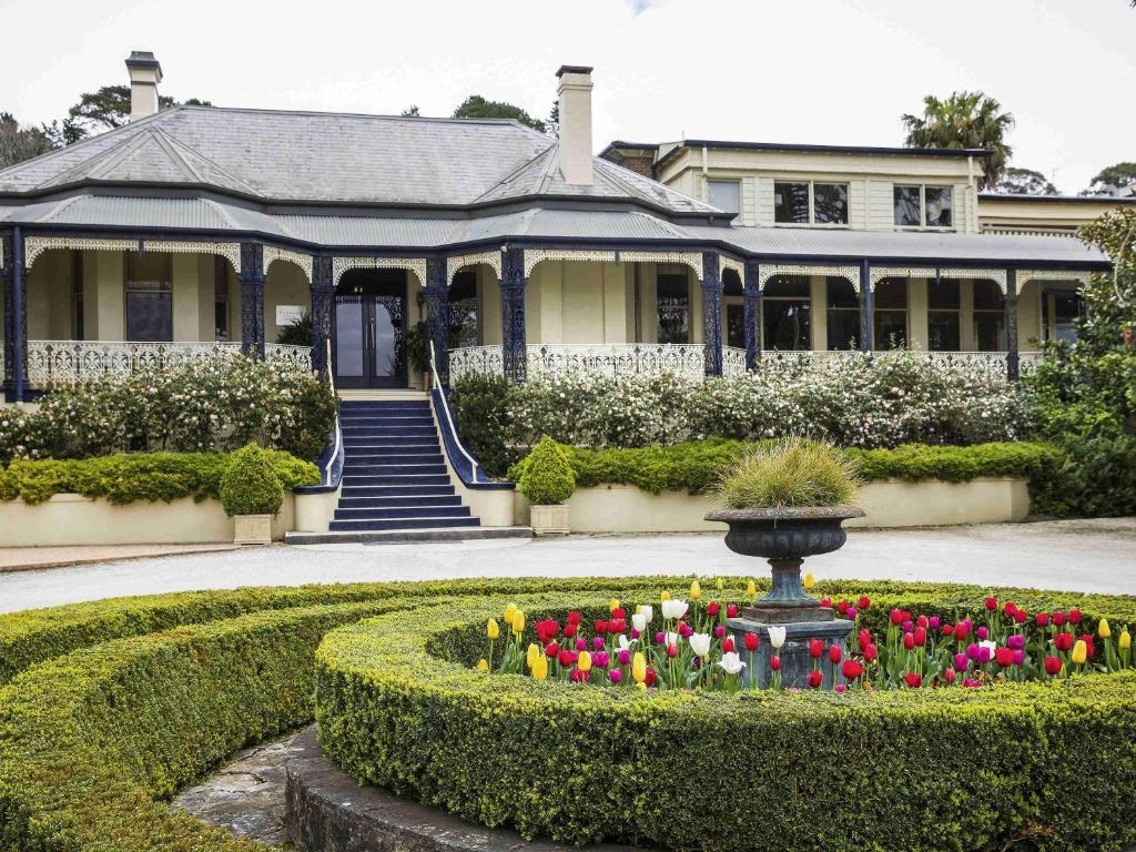 a house with a garden with a fountain and flowers at Peppers Craigieburn Resort in Bowral