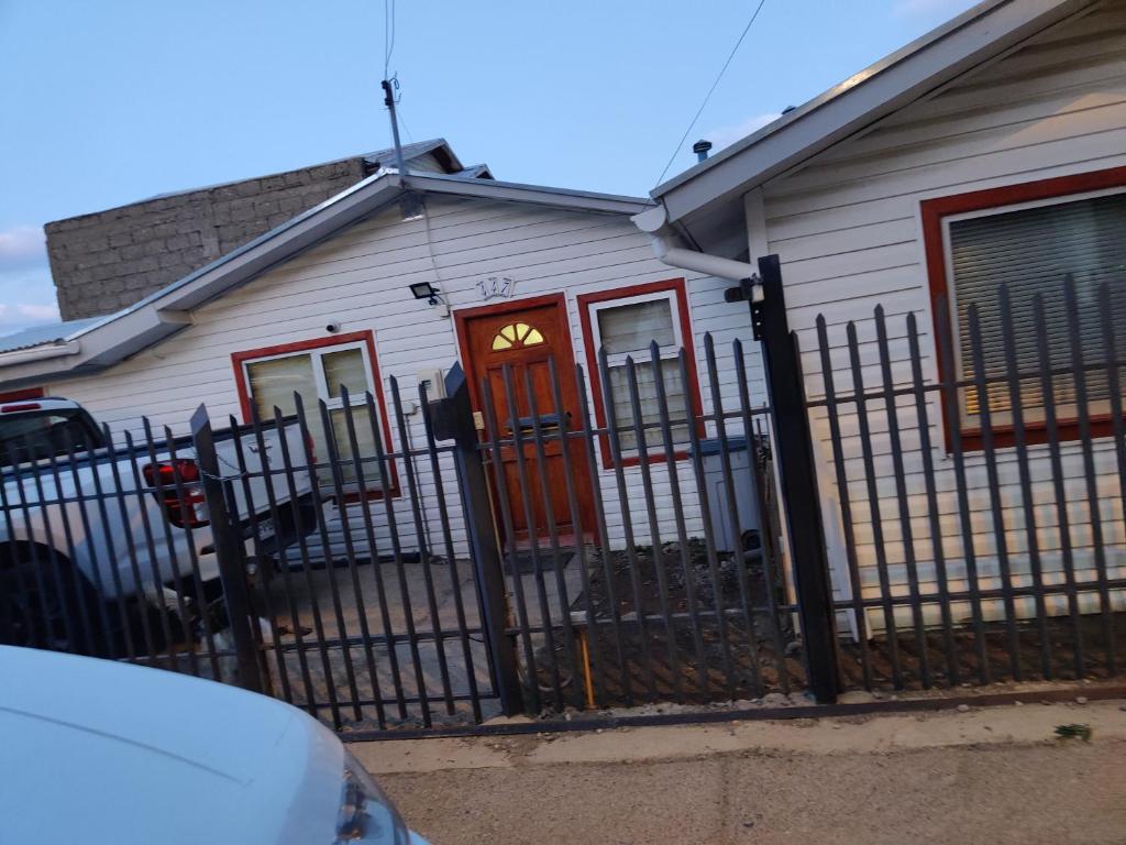 a white house with a red door and a fence at Casa amoblada en Punta arenas in Punta Arenas