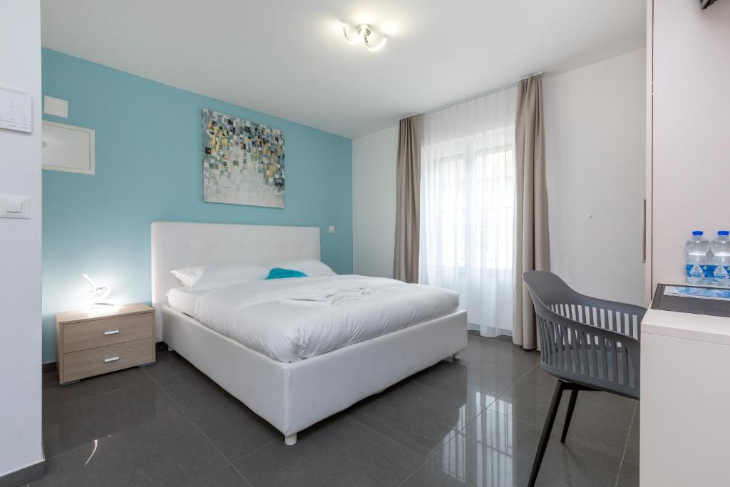 a bedroom with a white bed and a chair at Hotel Kernhof Self Check-In in Zurich