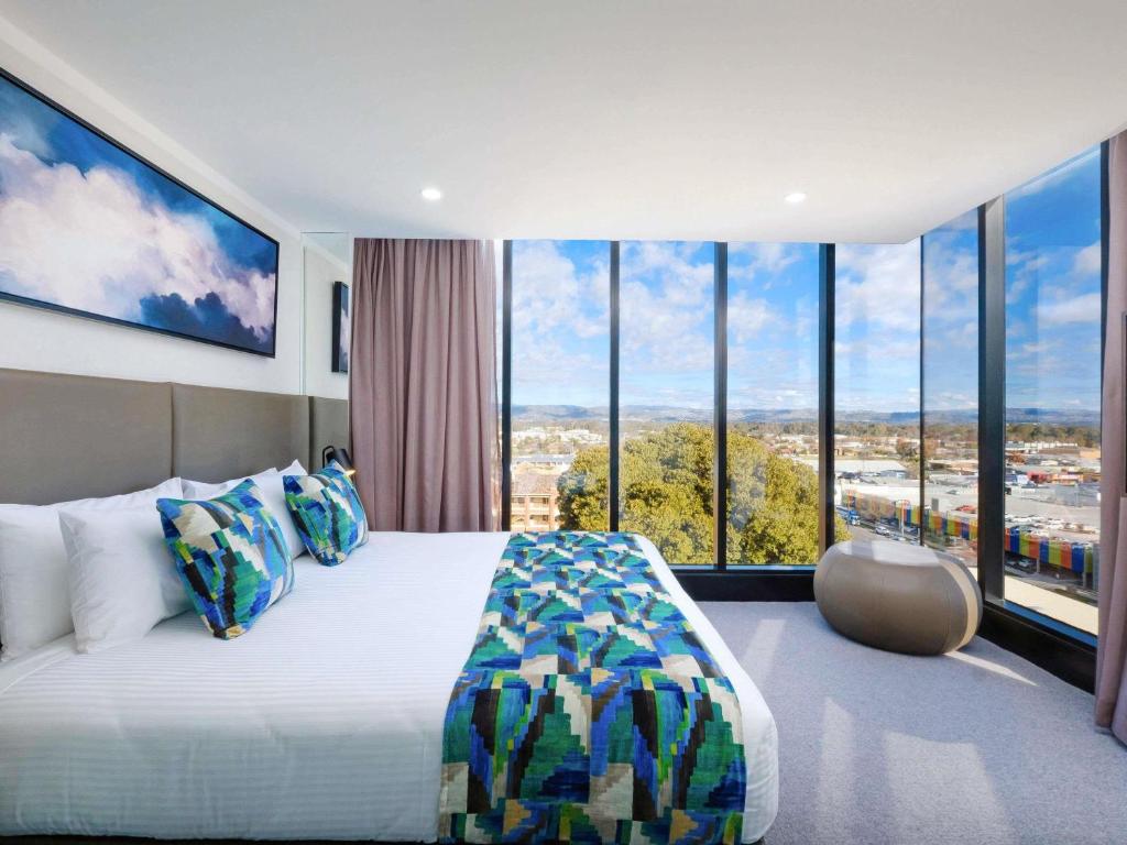a bedroom with a large bed and large windows at Mantra Albury in Albury