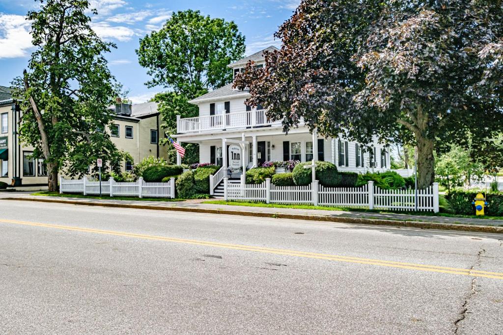 a white house with a white fence on a street at The Nicholson Inn in Freeport