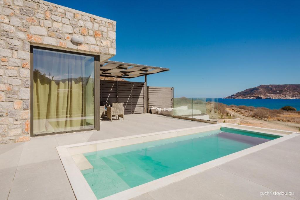 a swimming pool in front of a stone house at Relaxury Villa III in Karpathos