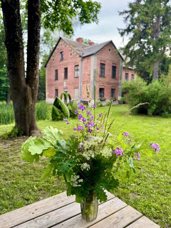 a vase of flowers sitting on a table in front of a house at Attic rooms-Bēniņu istabas in Jelgava