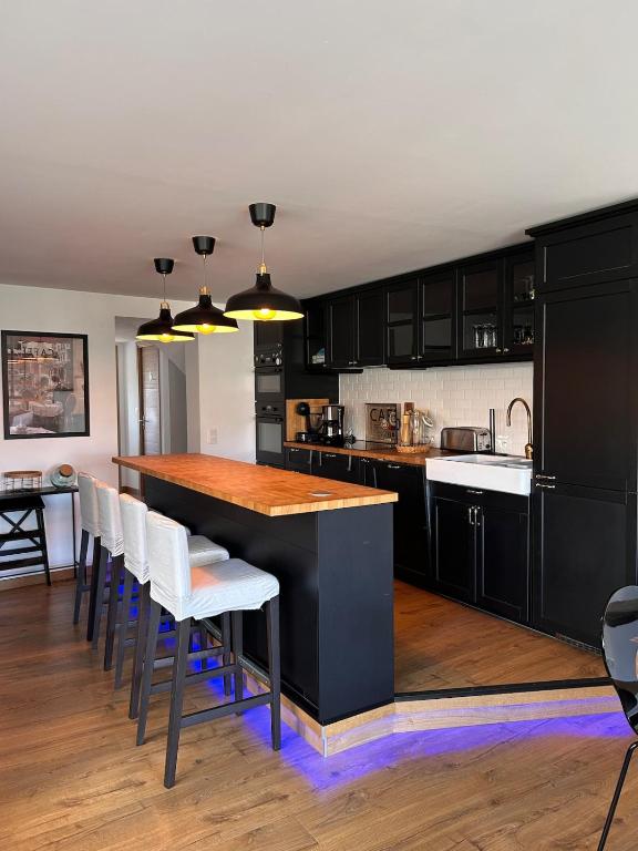 a kitchen with black cabinets and a island with bar chairs at La Fabrique - Relaxing break with Jacuzzi in Crécy-en-Ponthieu