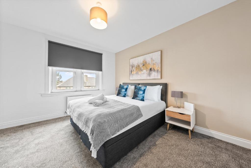 a bedroom with a large bed with blue pillows at Lesmahagow Hilltop View in Lesmahagow