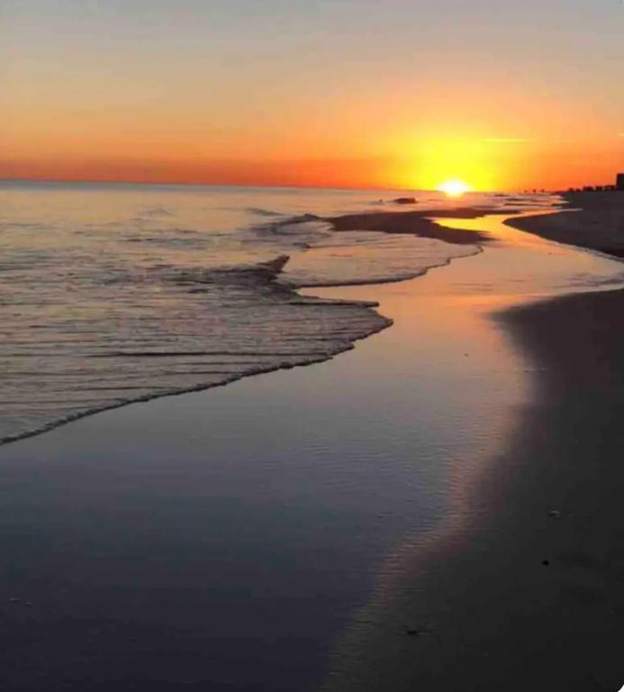 a sunset on the beach with the tide coming in at Pura Vida in Navarre