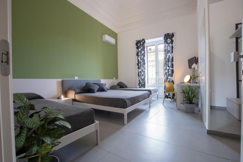 a bedroom with two beds and a couch at Suite Inn Catania in Catania