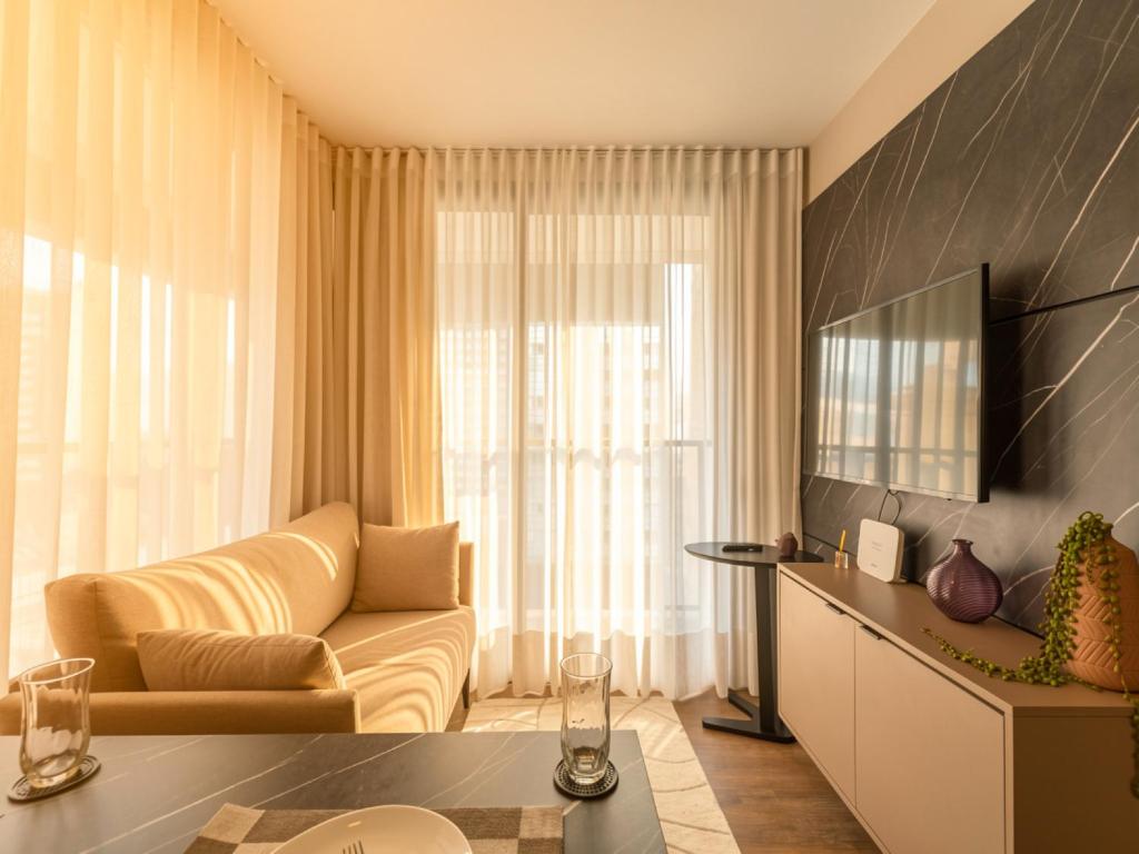 a living room with a couch and a television at Campos Sales by Xtay - Studios completos na região judiciária de Juvevê in Curitiba