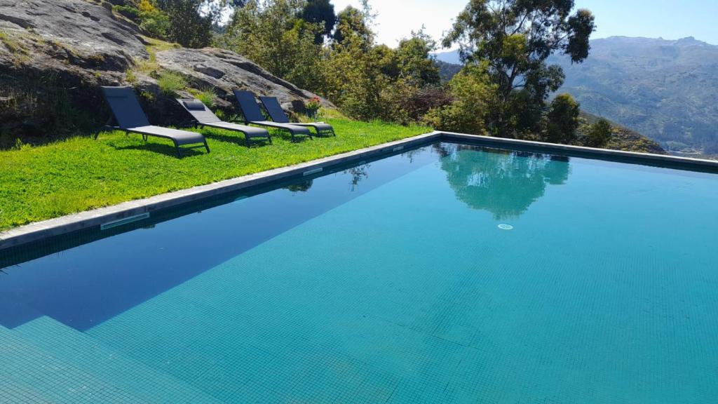 a swimming pool with chairs and mountains in the background at Quinta da Riba Má in Santa Leocádia