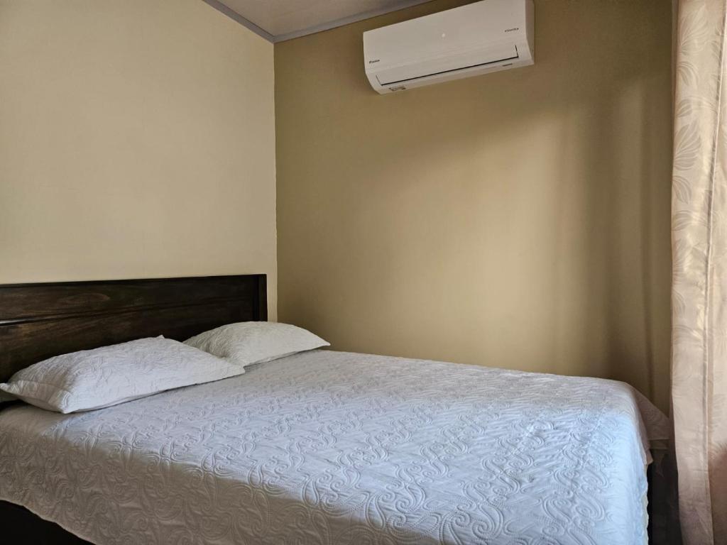 a bedroom with a bed with two pillows and a air conditioner at MarLis in Quebrada Seca