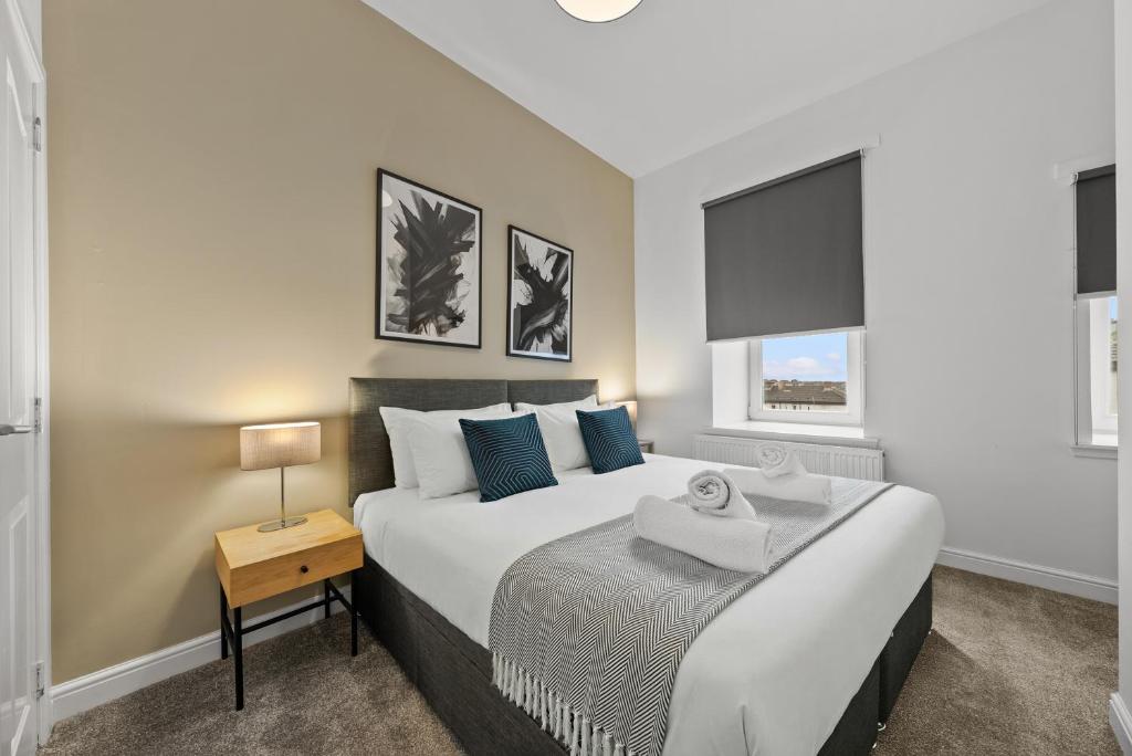 a bedroom with a large bed with a nightstand and a window at 1-Bed Duplex with Sofa Bed in Airdrie Lanarkshire - Long Stays - Free Parking in Airdrie