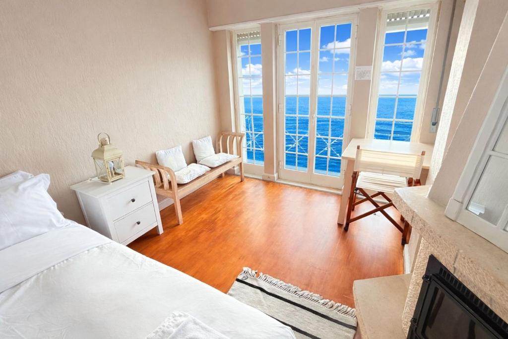 a bedroom with a bed and a living room with the ocean at Atlantic Views Sintra Guest House in Colares