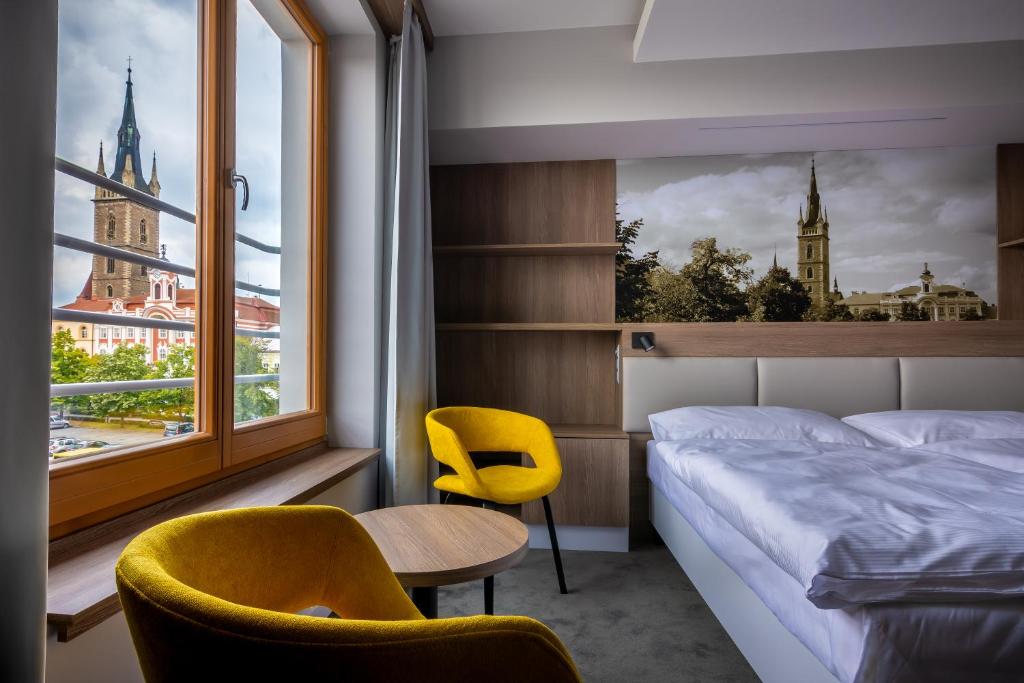 a bedroom with a bed and two chairs and a window at Hotel Grand in Čáslav