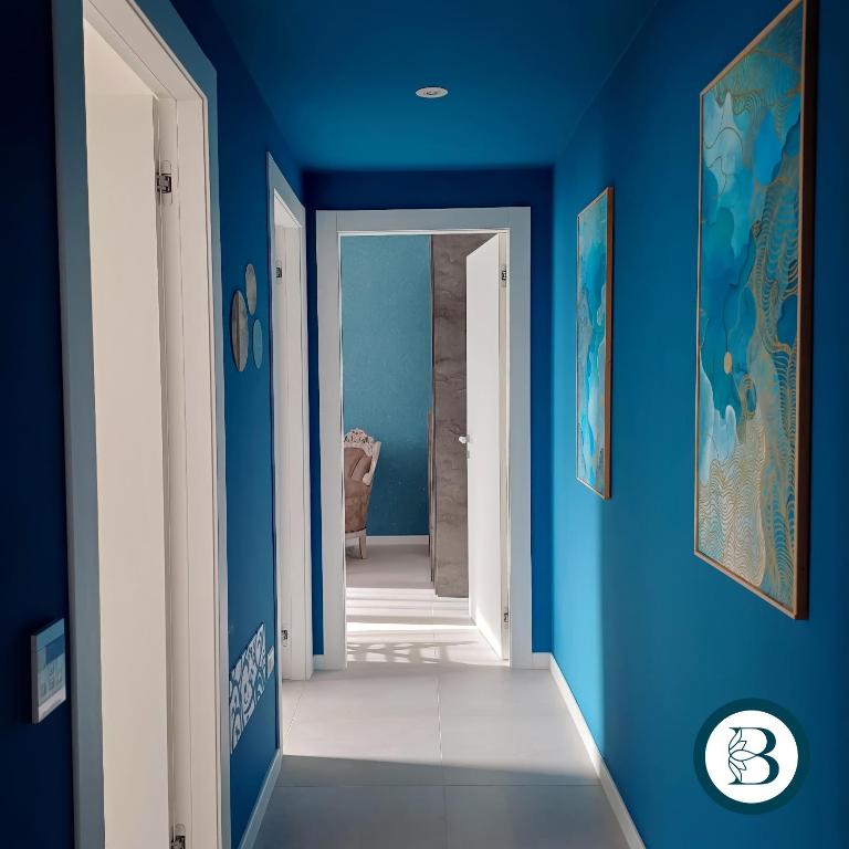 a hallway with blue walls and an open door at BlueCharme modern apartment in Quartu SantʼElena
