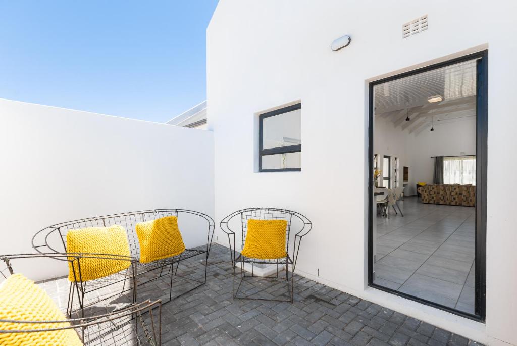 a patio with yellow chairs and a large window at The North Atlantic Sands Beach House in Velddrif