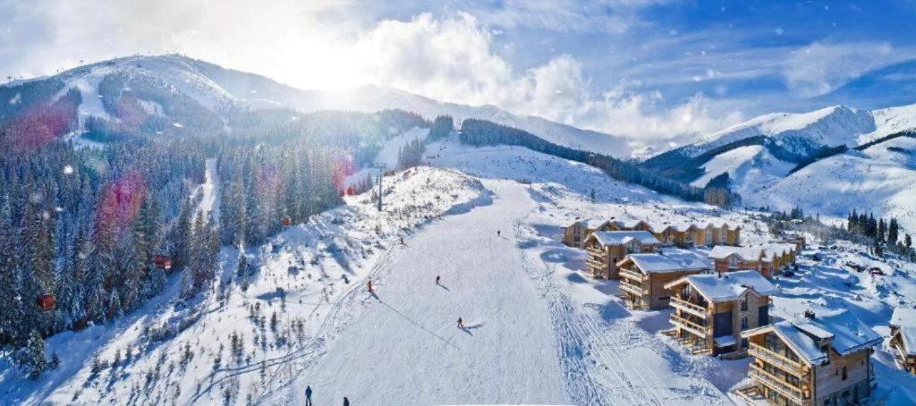 a snow covered mountain with a ski resort in the distance at Chalets Jasná Centrum APARTMENT S - Free Jacuzzi & Sauna and Chopok view in Belá