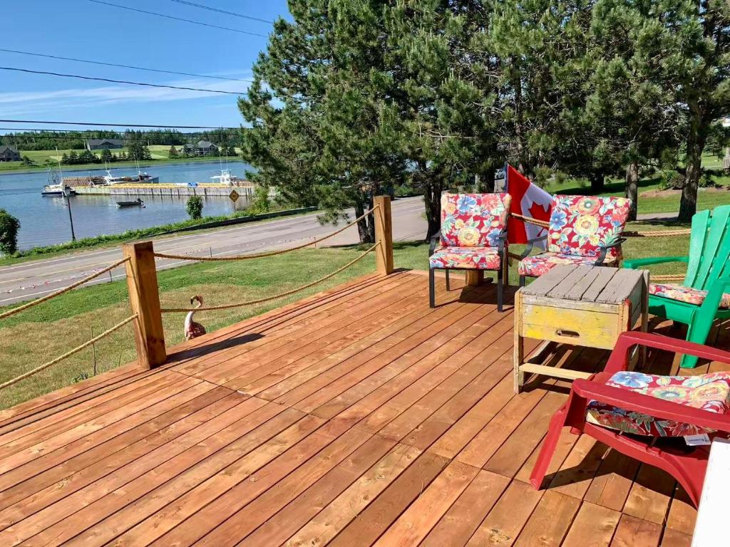 a wooden deck with two chairs and a table at 101 Harborview Drive in North Rustico