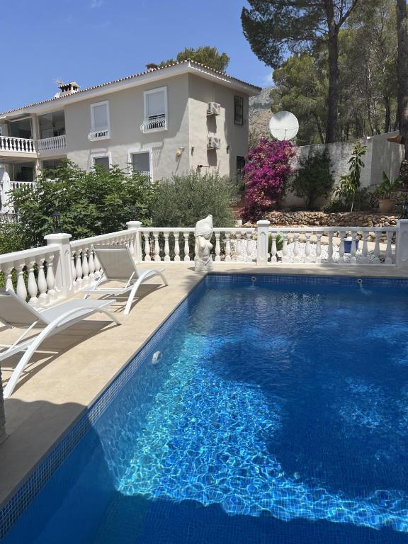 ein Schwimmbecken mit zwei Stühlen und ein Haus in der Unterkunft Villa Serenity in Altea