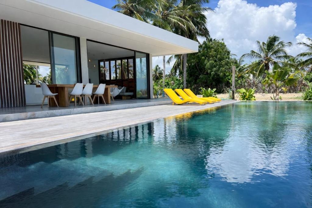 a swimming pool with yellow chairs next to a house at Le rêve des kitesurfeurs in Itarema