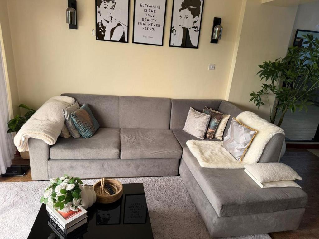 a living room with a gray couch and a table at Sweet Haven - Sports Rd in Westlands